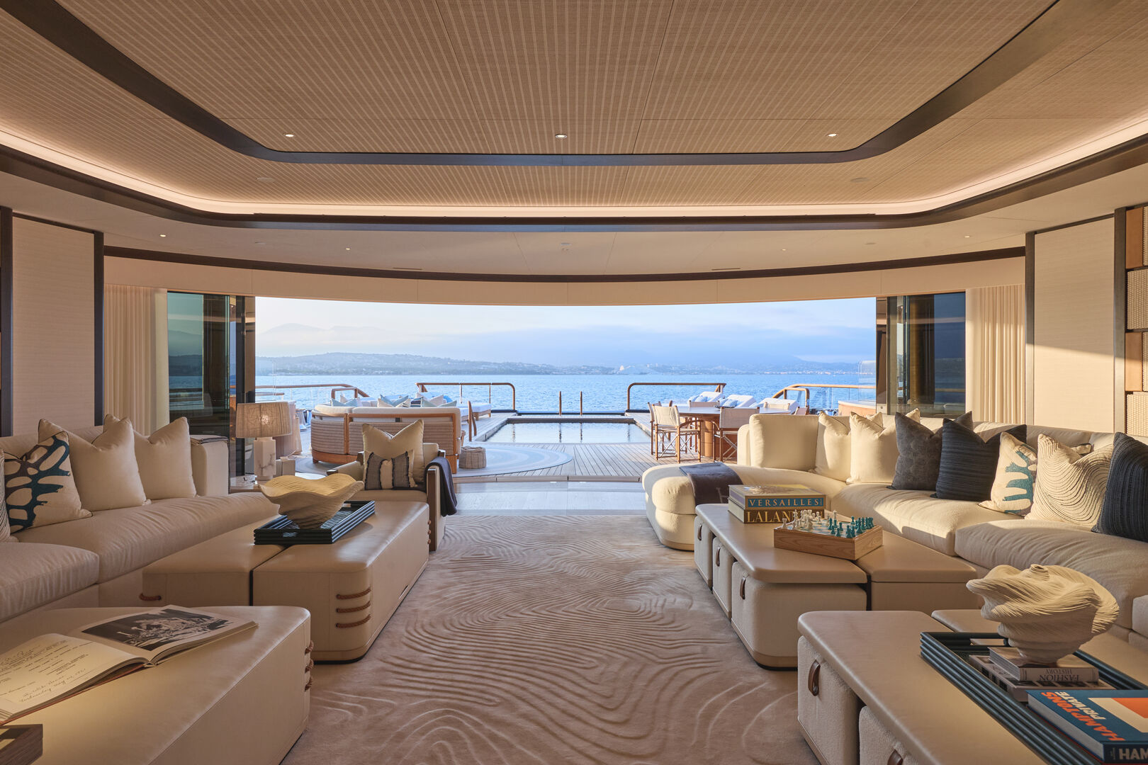Superyacht main salon opening onto the aft deck and pool